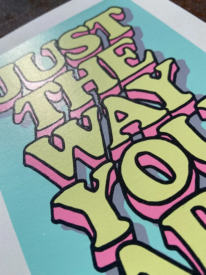 "Just The Way You Are” Mini A5 Hand Pulled Screen Print In pastel blue with the words just the way you are in hand drawn lettering printed on top with black outline and pink and yellow fill