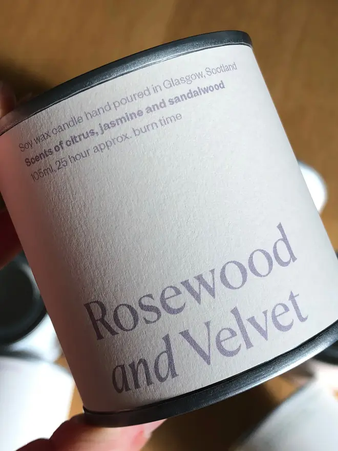 Rosewood & Velvet Candle against a wooden background. 