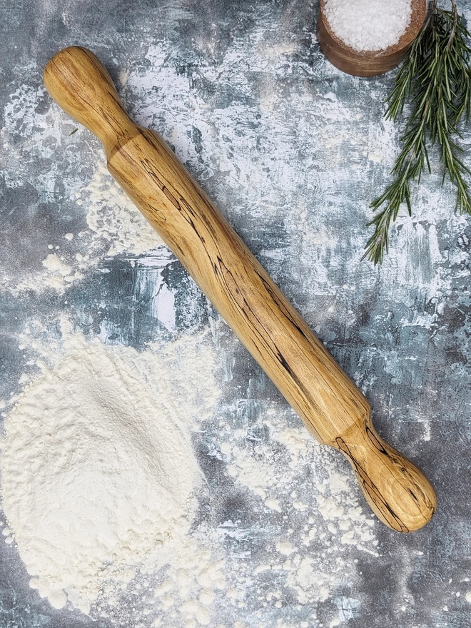 A stunning hand made rolling pin in Spalted Beech by Something From The Turnery. The rolling pin sits on an art house kitchen top amongst flour and fresh rosemary, prepped to bake some delicious bread!