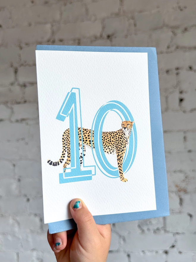a white card with a big blue number 10 and an illustration of a cheetah with a pale blue envelope