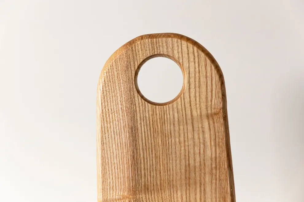 Ash Paddle Serving Board, a wooden serving board sat on a plain surface.