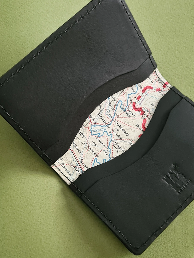 detail of a rare silk war map lining a black leather card holder by natthakur