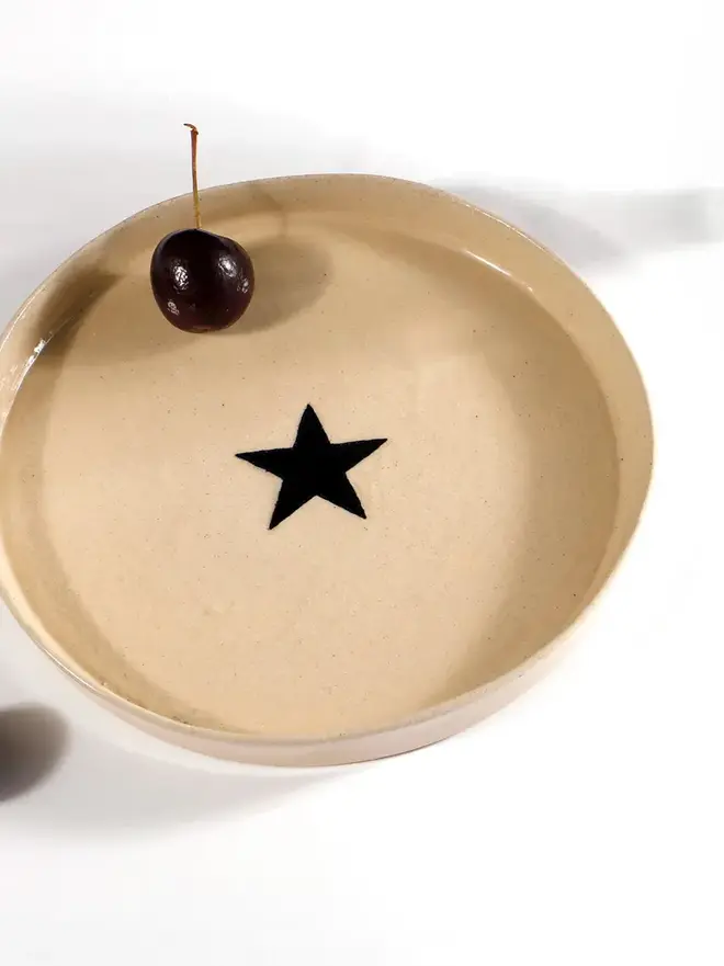 Handmade Ceramic Side Plate With A Black Star Design, a ceramic side plate with a black star design sitting on a white table. 