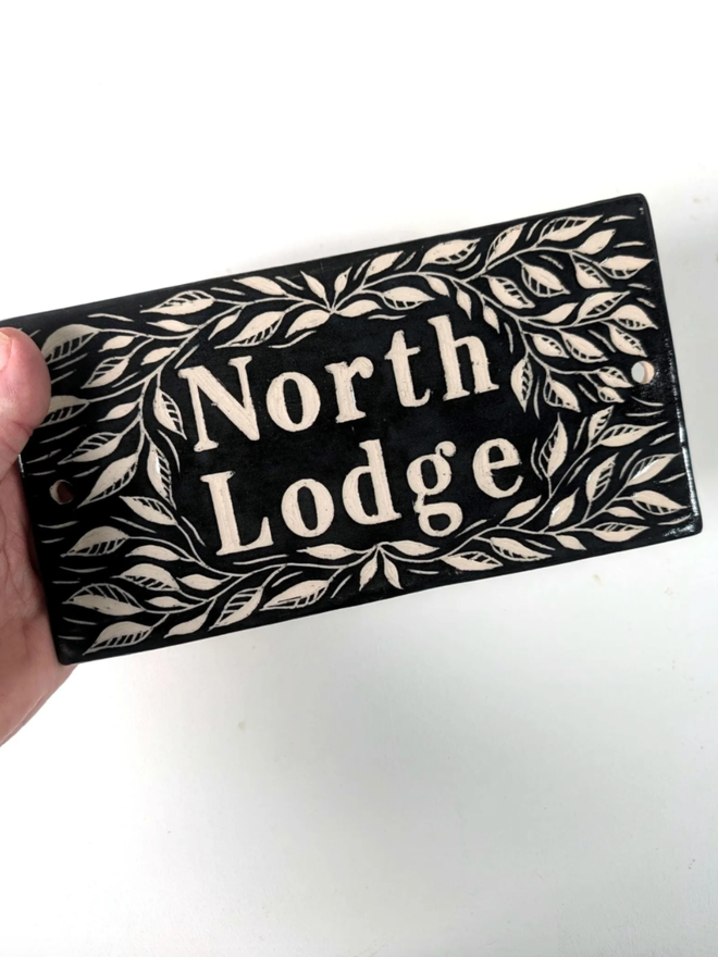 Handmade Ceramic House Plaque with Leaf Pattern. A plaque in black.