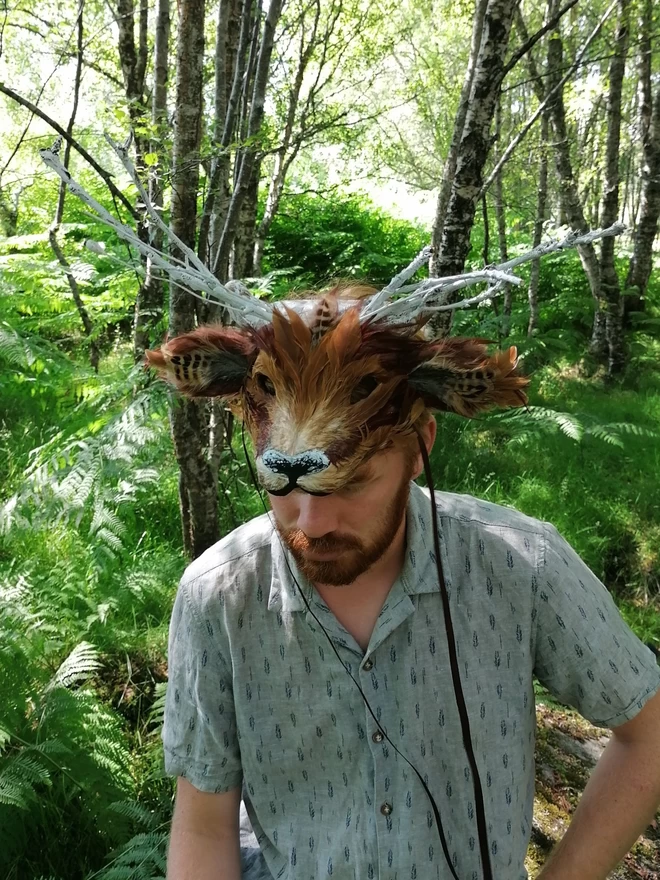 A man wearing a luxury brown deer part mask atop his head as a headdress