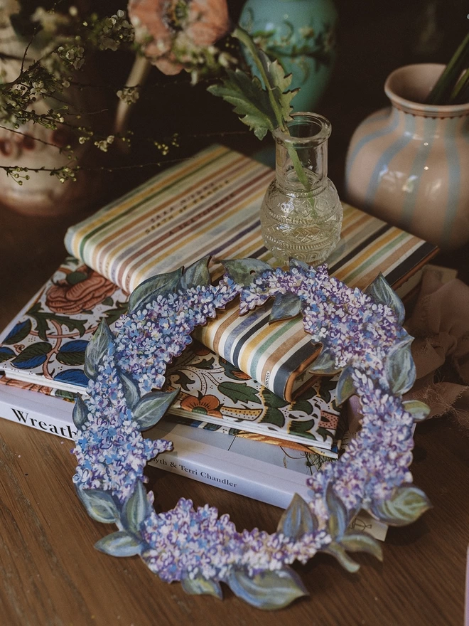 Wooden Lilac Garland, set amongst some books and fresh flowers
