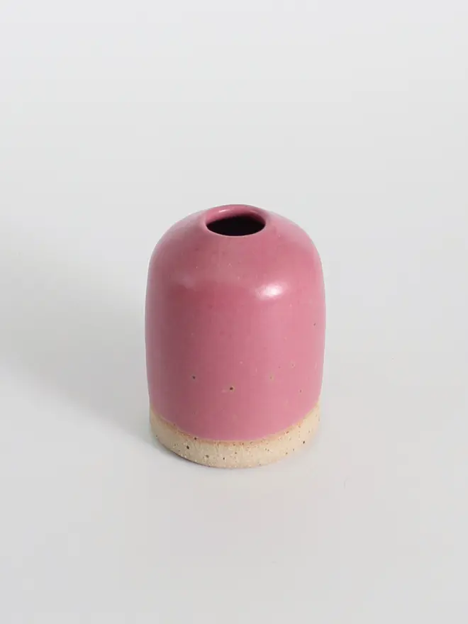 Small fuchsia ceramic vase against a white background.