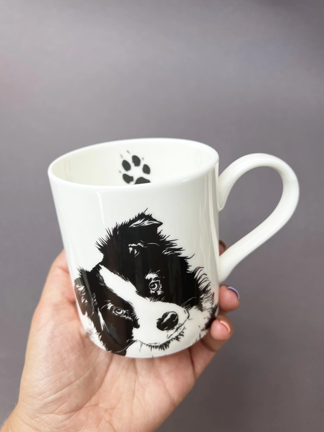 Black and white border collie mug showing the cute collie paw on the inside