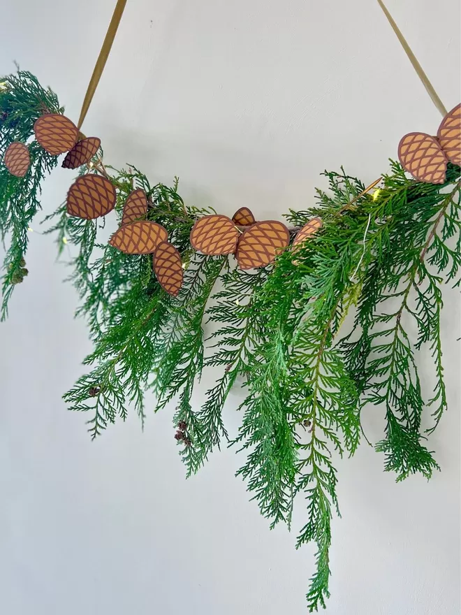 Pinecone Paper Garland displayed on hanging bough of winter foliage