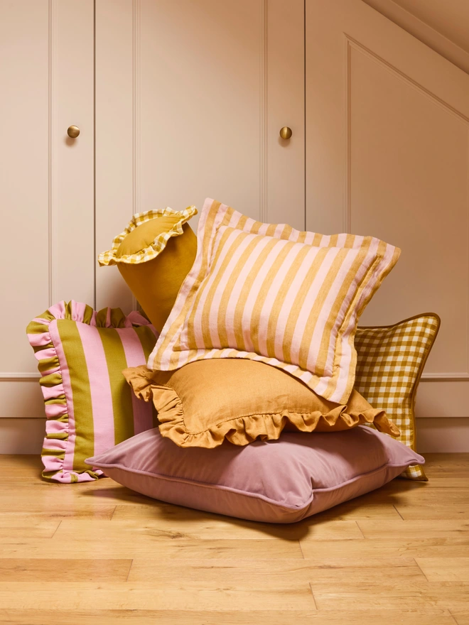 Handmade peach and mustard stripe linen cushions styled in bedroom cushion arrangement, Kika Bespoke