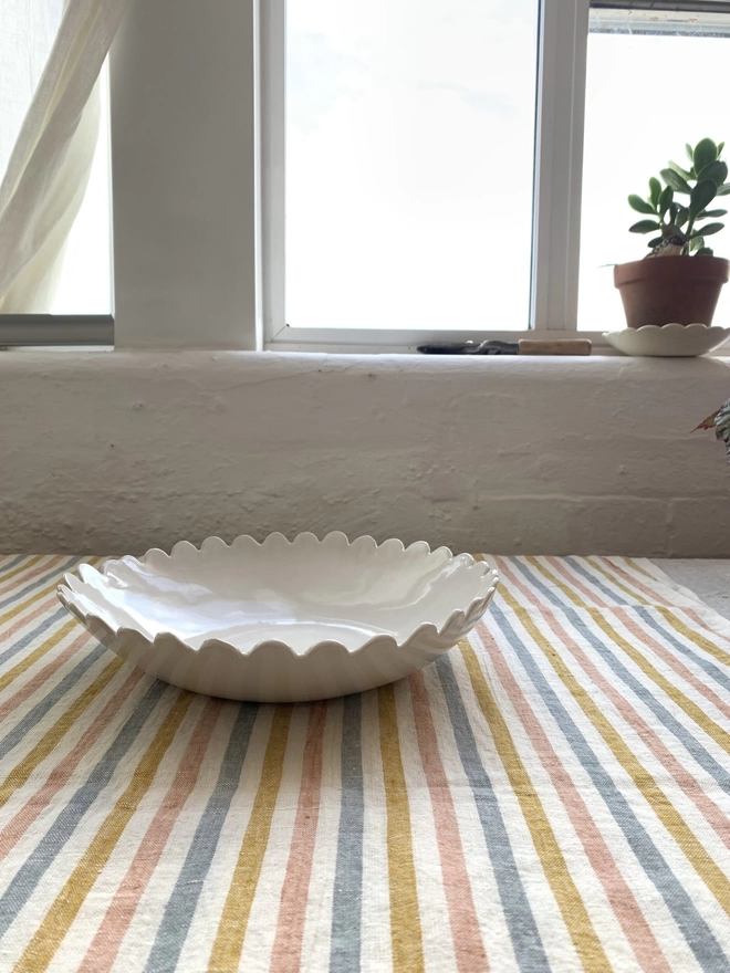 Side view white medium sized serving bowl with scalloped edge