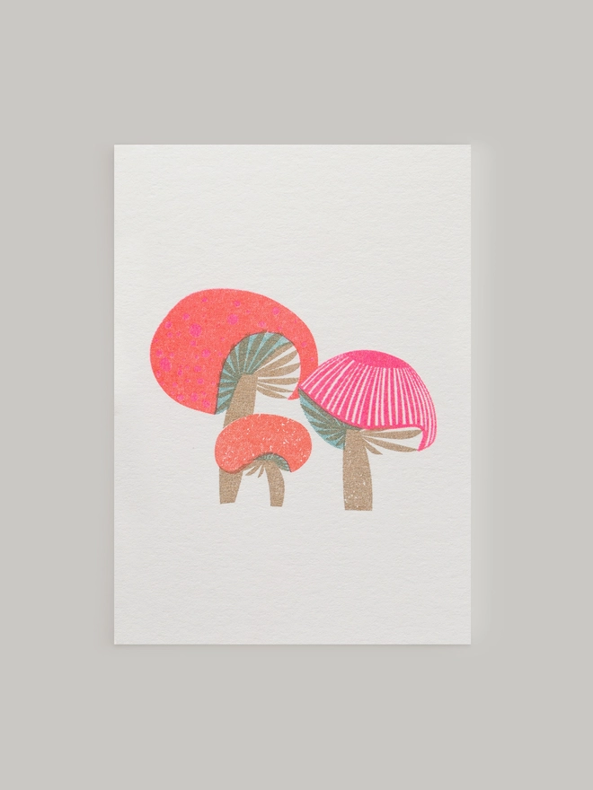 A cute little trio of pink and red toadstools and mushrooms are risograph printed in beautifully vibrant colours on this sweet little greeting card. The mini mushrooms are highlighted with touches of subtle metallic gold ink which makes this card an extra special way to send messages of love and friendship. Each card comes complete with a contrasting envelope and is blank inside.