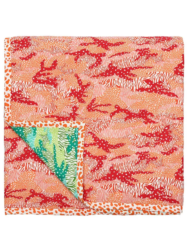 Big Cat Camo quilt, reversible orange and green camouflage and animal print quilt folded on a white background.