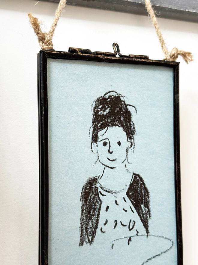 sketchy portrait of girl on blue paper in metal frame