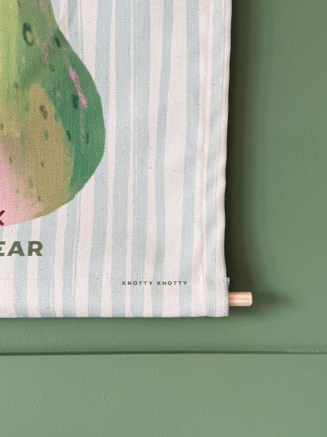 Cotton Pear Wall Hanging, hanging on a green wall. 