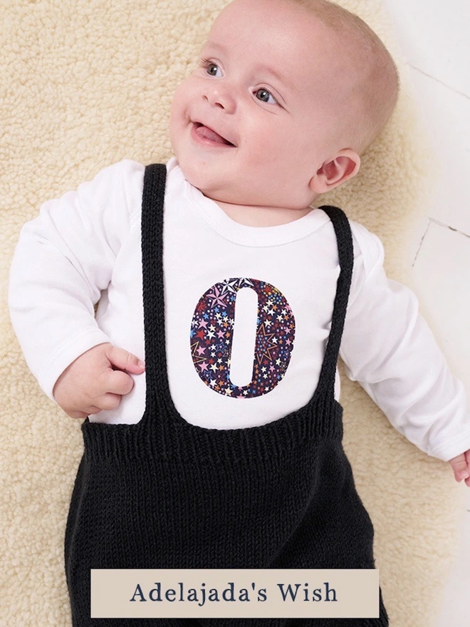 a new baby in a Liberty print initial baby bodysuit in a star print
