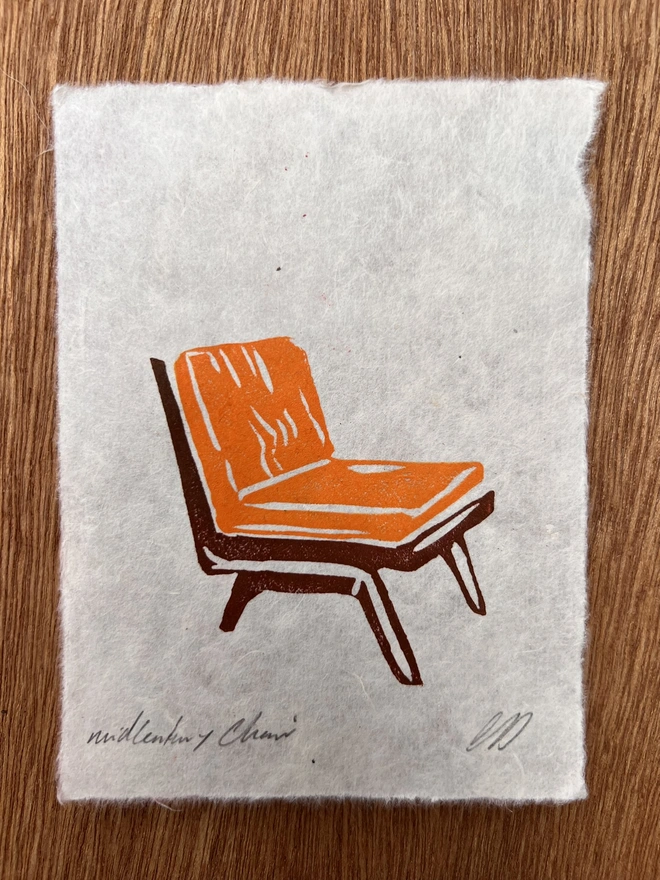 Hand-printed mini vintage orange chair lino print on natural handmade paper, featuring a bold retro illustration of a mid-century chair.