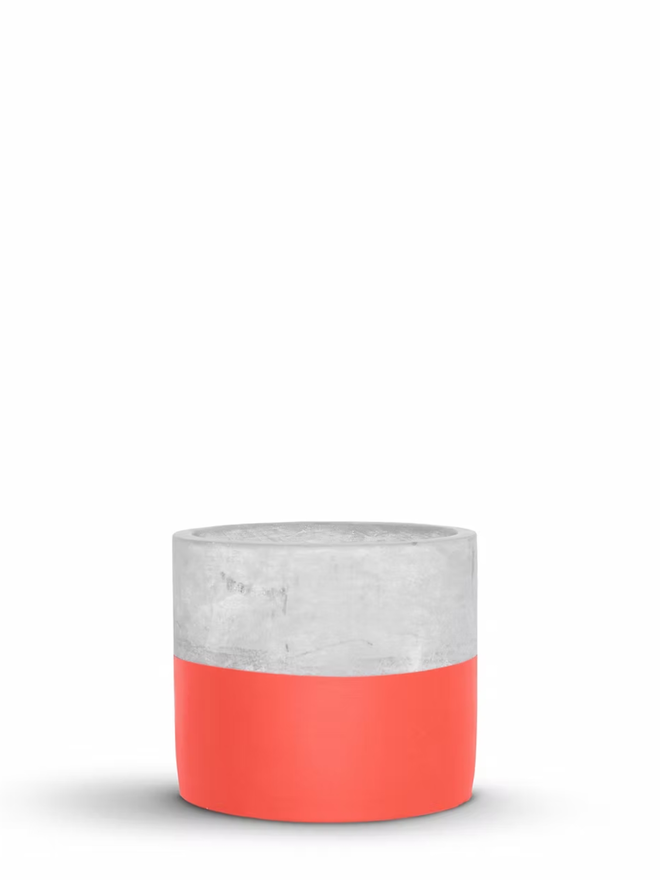 half full concrete plant pot. a grey concrete plant pot with the bottom half painted coral.