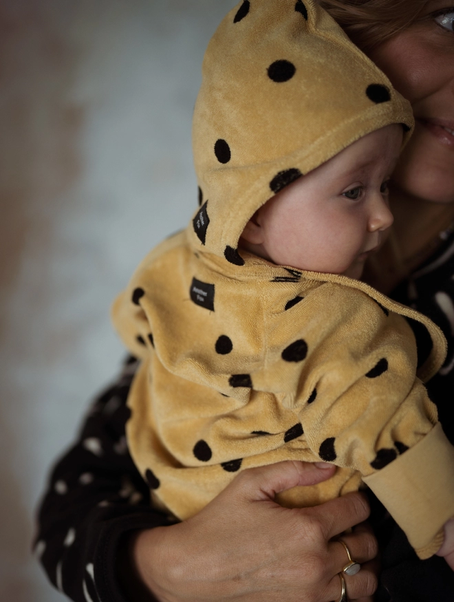 Close up of the Another Fox Camel Terry Towel Spot Baby Sleepsuit with its hood up.