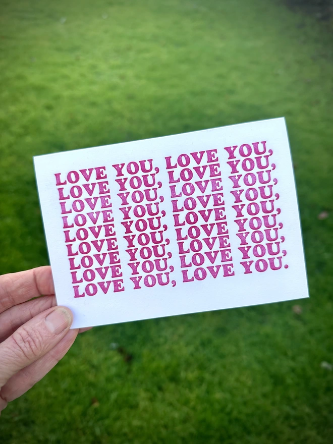 Love You letterpress printed card in hand against green background