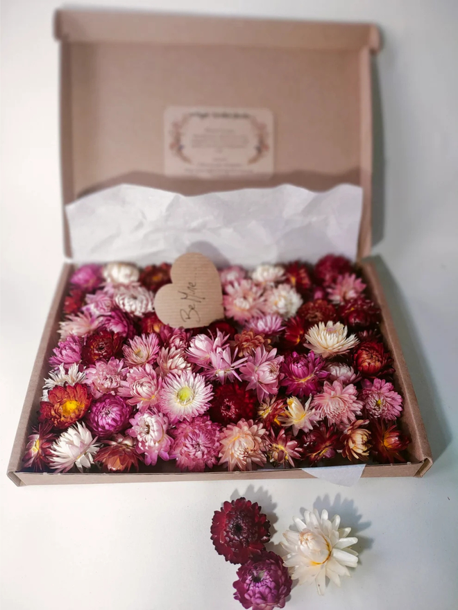 box of pink dried flower heads. selection of pink dried flower heads presented in cardboard gift box.