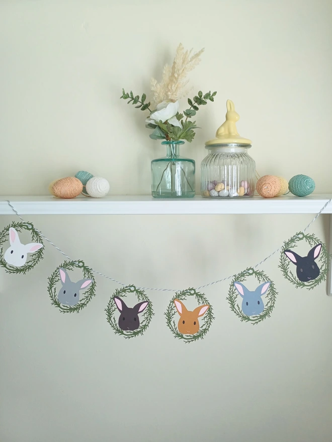 Easter Bunny Garland (6 Bunny Option) decorations are threaded onto grey and white bakers twine and hung from a shelf