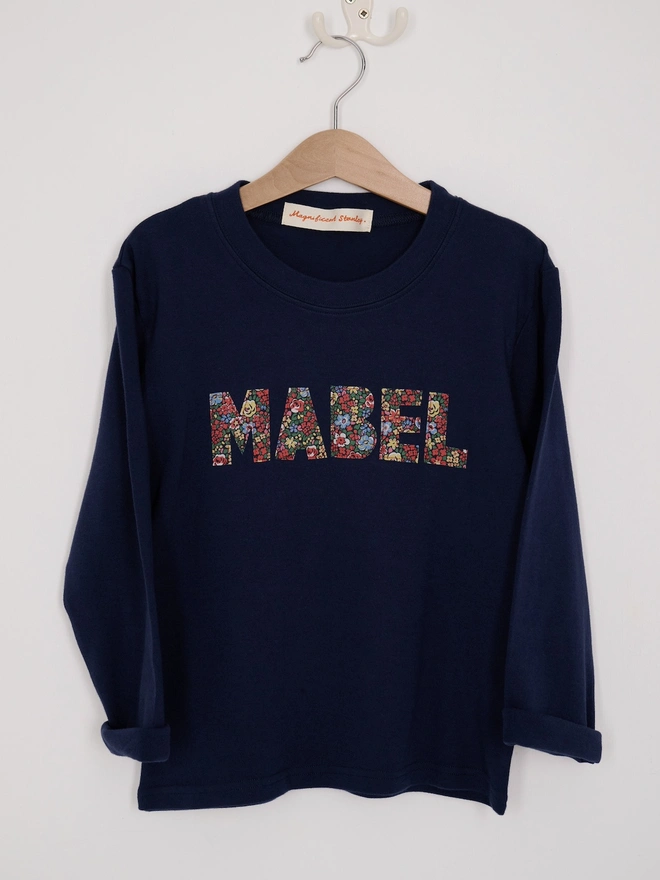 a navy long sleeve t-shirt with her name Mabel cut from Liberty floral fabric and sewn onto the front 