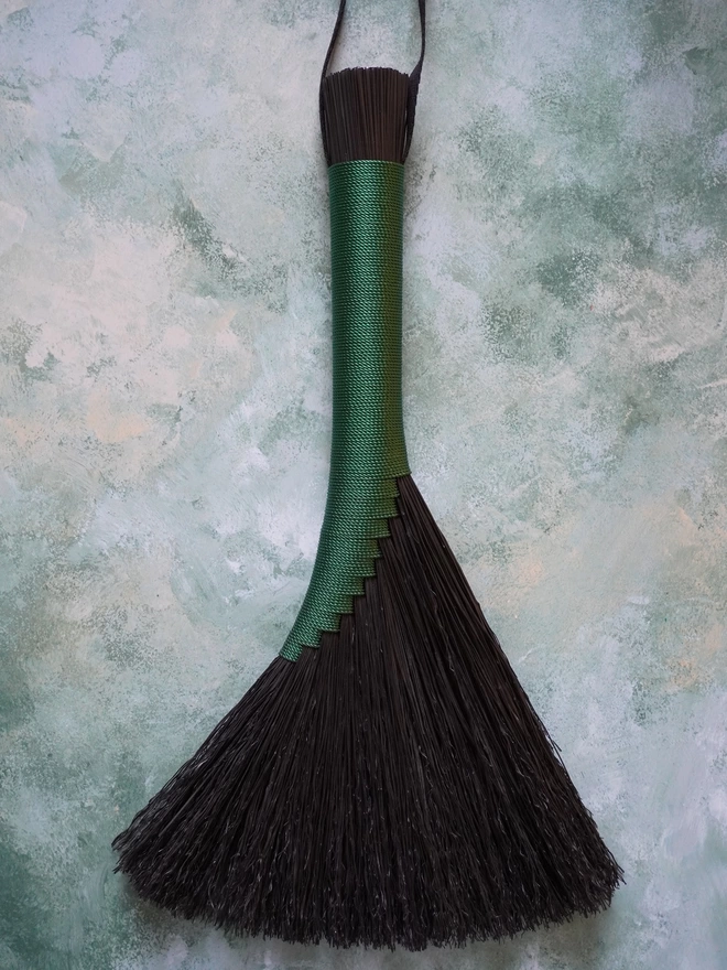 Black broomcorn handbroom with green nylon cord binding