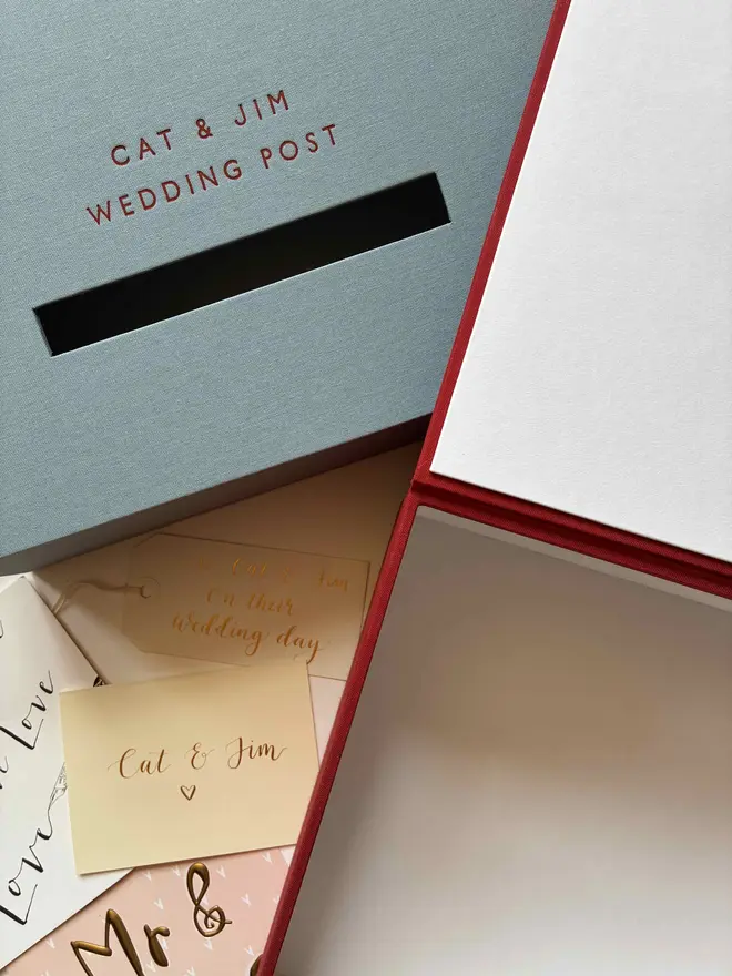 Two handmade wedding postboxes, one in Powder Blue book cloth and one open in traditional post box red with foiled details