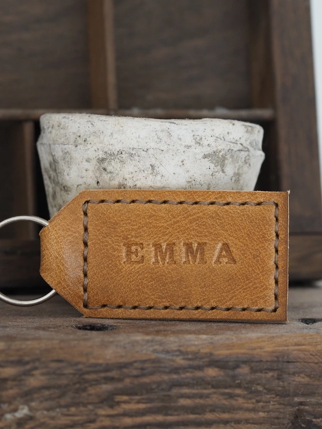Personalised tan brown leather keyring. Hand stitched with golden brown thread and stamped with the name EMMA.