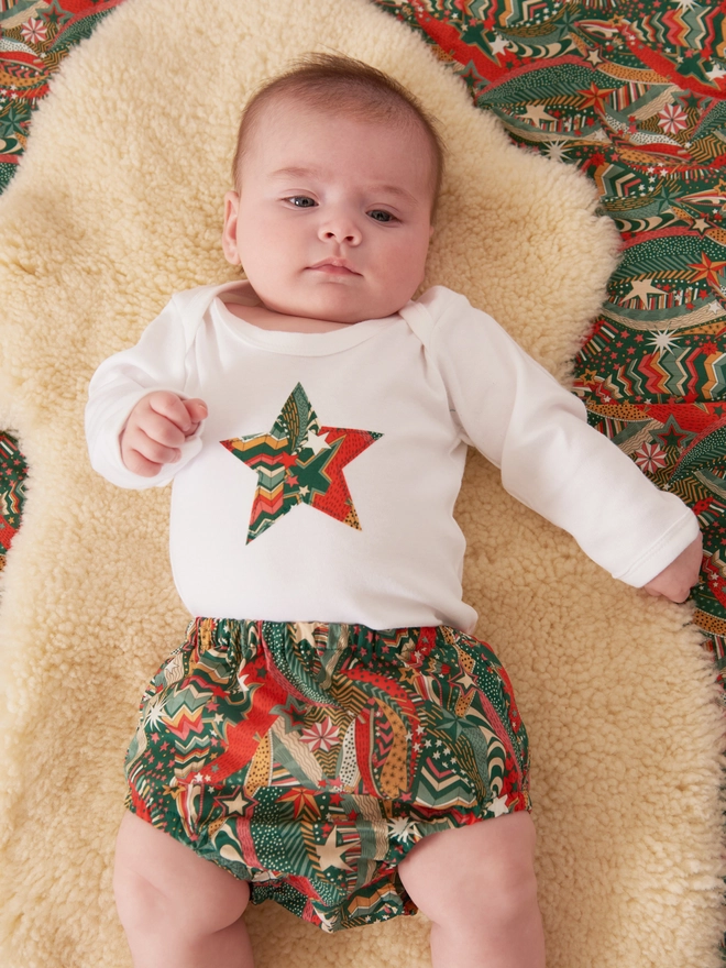 a new baby wearing a christmas liberty print starry print star white bodysuit