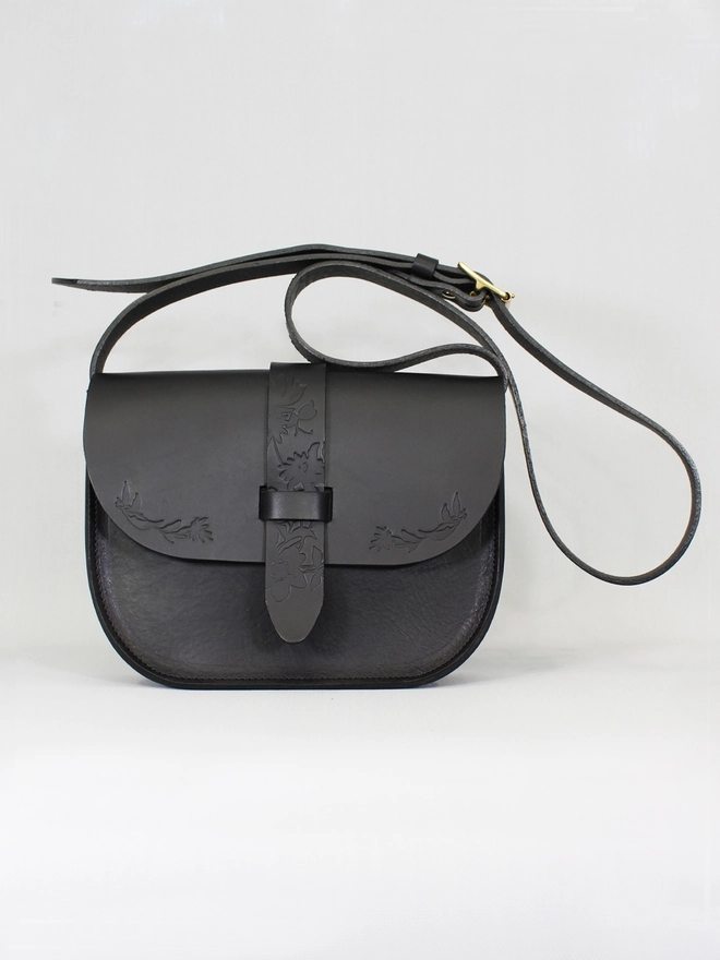 a black natural leather long lasting crossbody bag with an adjustable strap for women featuring blind embossed floral details by natthakur