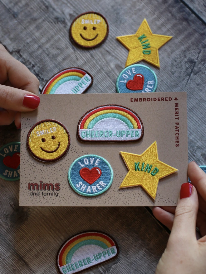 a set of four iron on embroidered patches with a kind star, smiley face, cheerer upper rainbow and love heart love sgharer