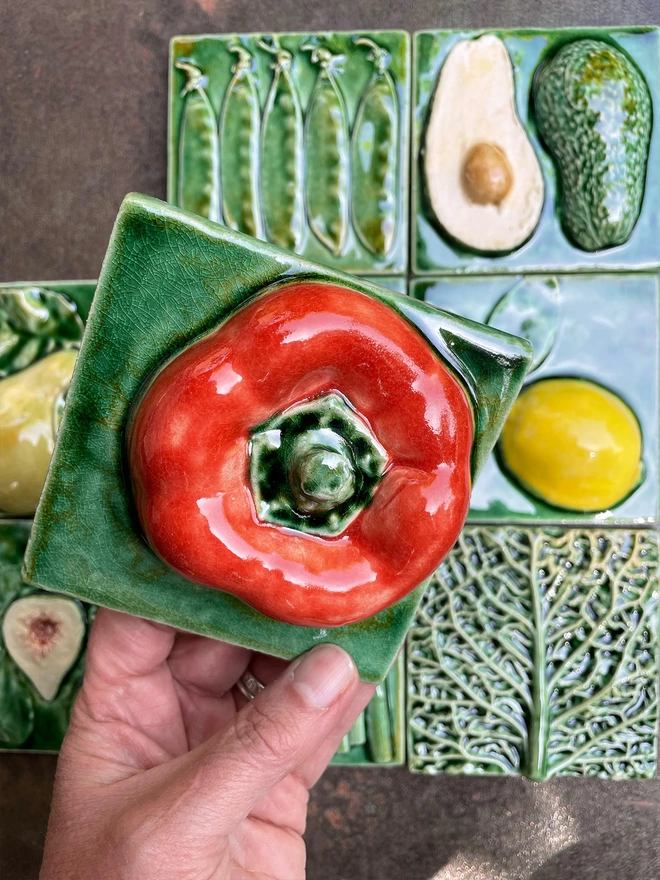 Red capsicum pepper tile - square, 3D, realistic and glossy. Other fruit and vegetable tiles in the series are on display in the background: lemon, fig, savoy cabbage, pear, mange tout, avocado, garlic, asparagus.