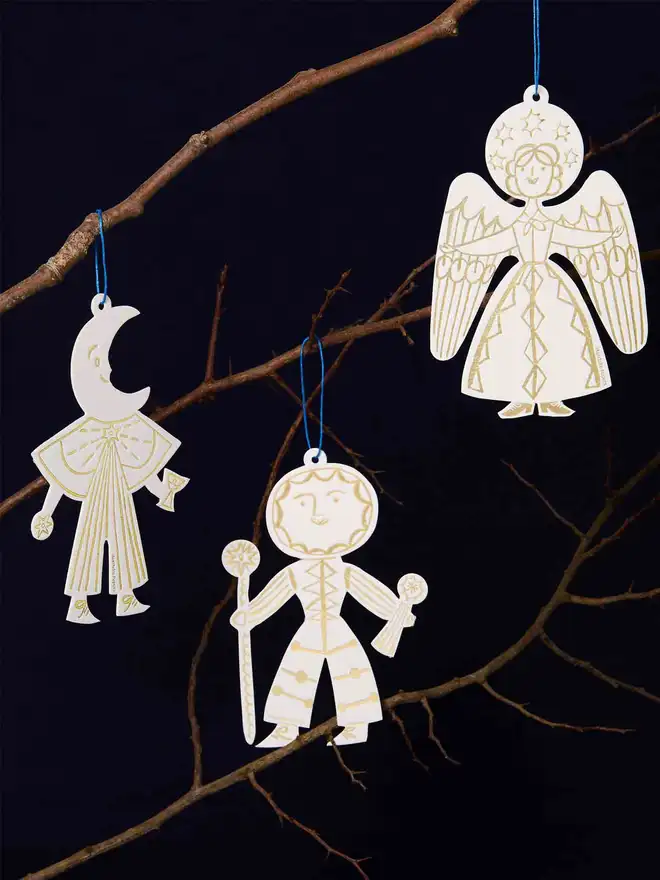  Decorative letterpress ornaments of celestial figures hanging on a branch against a dark background