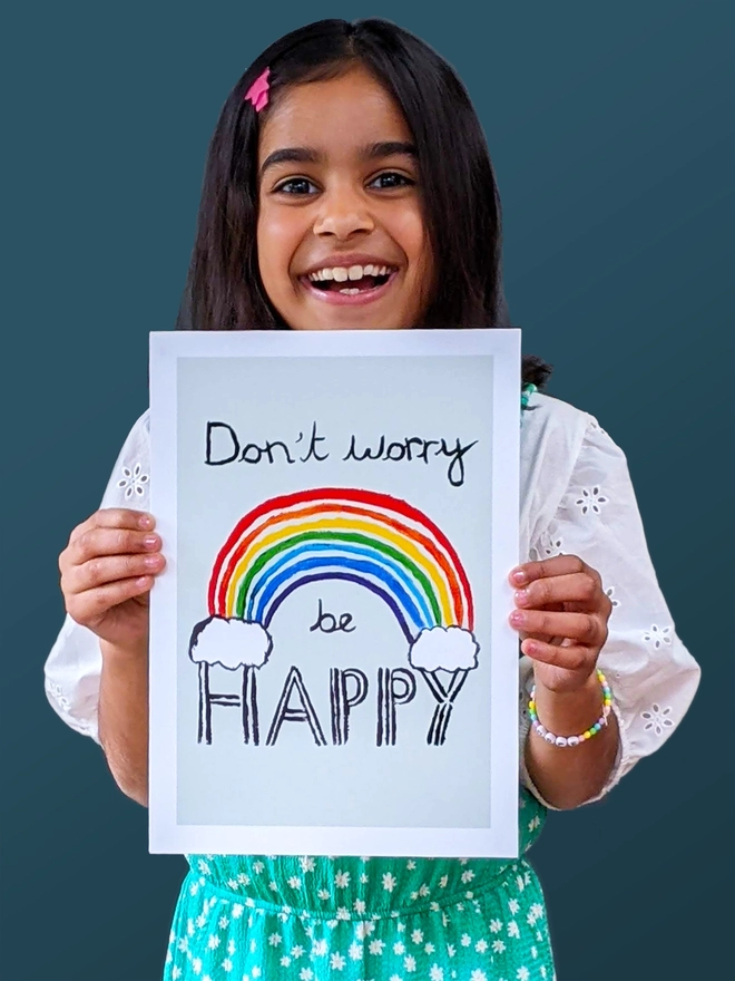 Young girl standing holding an art print saying 'Don't worry be happy'