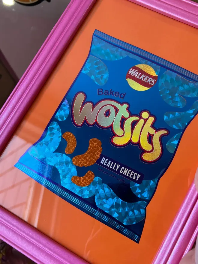 'Wotsits' ScreenPrint, a person holding a colourful wotsits screenprint in a frame. 