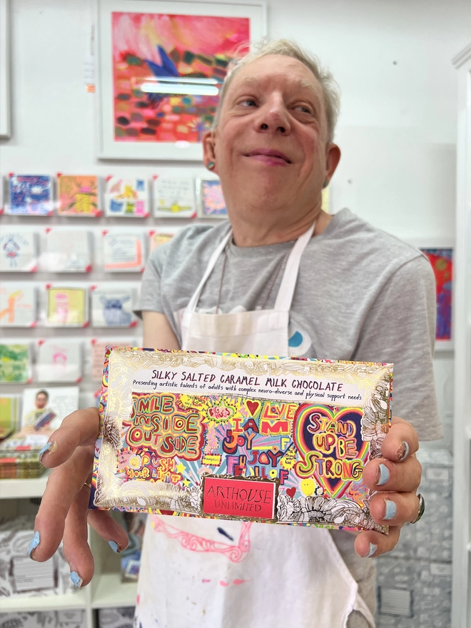 Artist holding Milk Salted Caramel Chocolate packaged in foiled card & bright positive messages