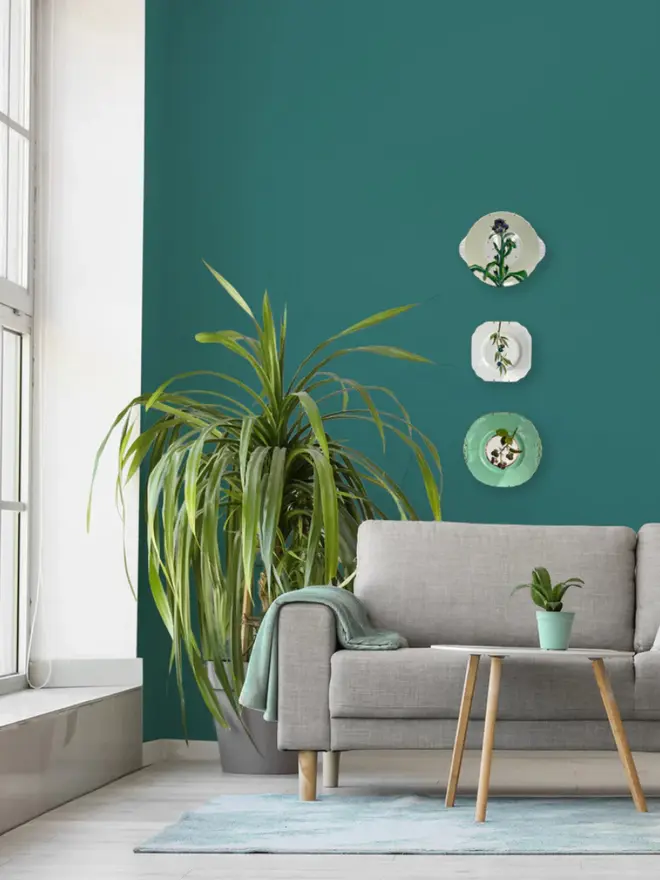 Oil Painted Sloe Berry Spray On A Vintage Tea Plate, hanging on a teal wall, amongst other paintings. 
