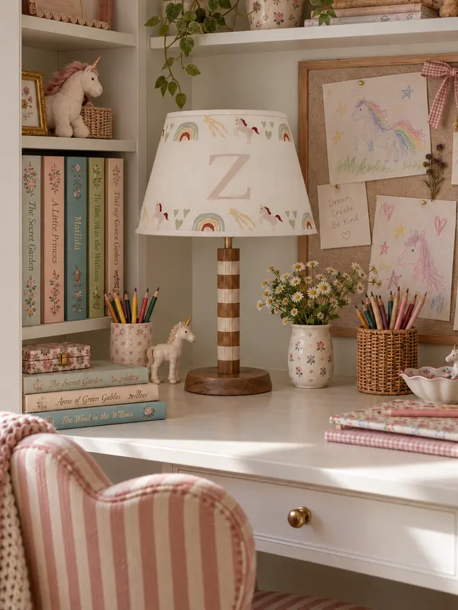 Personalised unicorn lampshade with initial Z, featuring hand-painted unicorns, rainbows, hearts and shooting stars, styled on a children’s desk.
