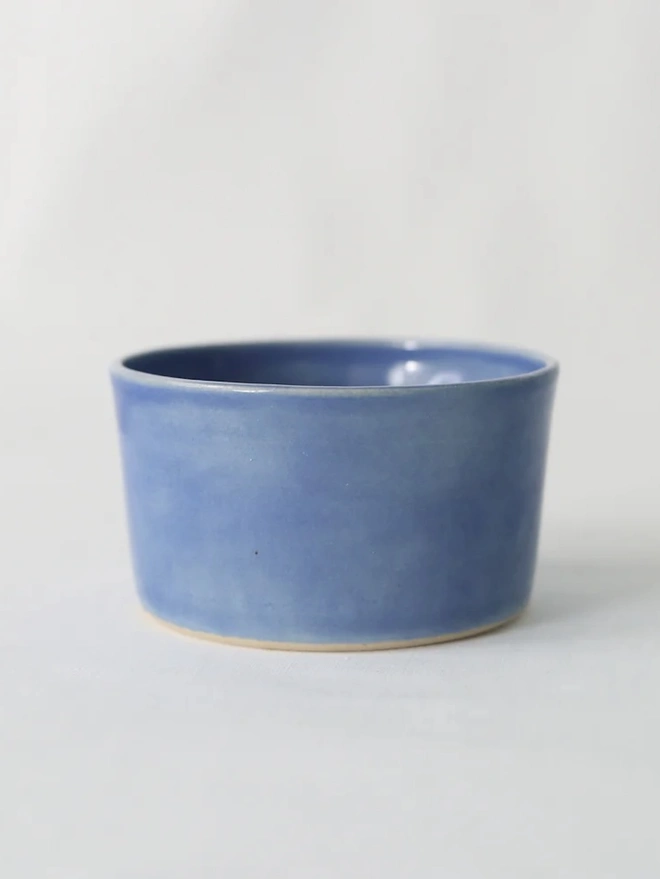 Classic Side Bowl, a colourful ceramic bowl on a wooden surface against a grey backdrop. 