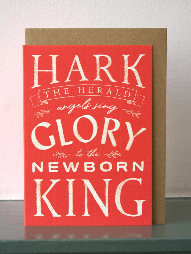 Red Christmas card with the words 'hark the herald angels sing' on the front