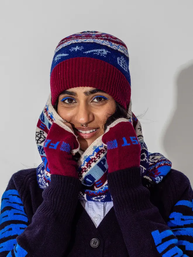 model is wearing our fairisle beanie and loop scarf in klein and claret with our feminist mittens in claret and our do no harm cardigan in navy and klein 