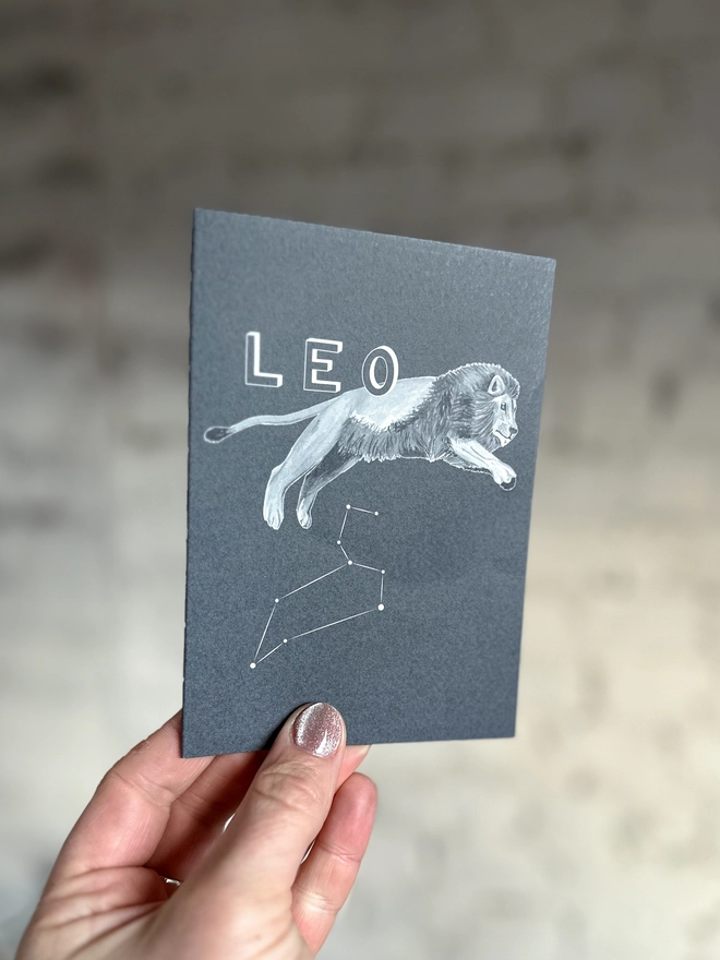 : a greetings card featuring a greyscale illustration of a zodiac style lion with the text “LEO”