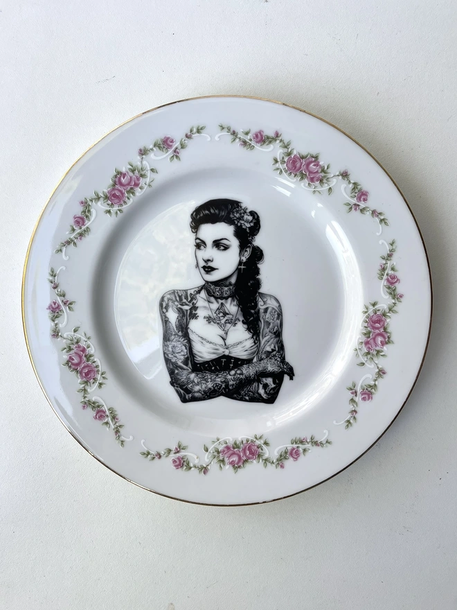 a vintage bone china plate with ornate border has a vintage Tattooed victorian lady in the centre