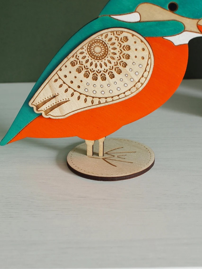 Standing Wooden Kingfisher, orange and blue wooden bird decoration standing on a platform. 