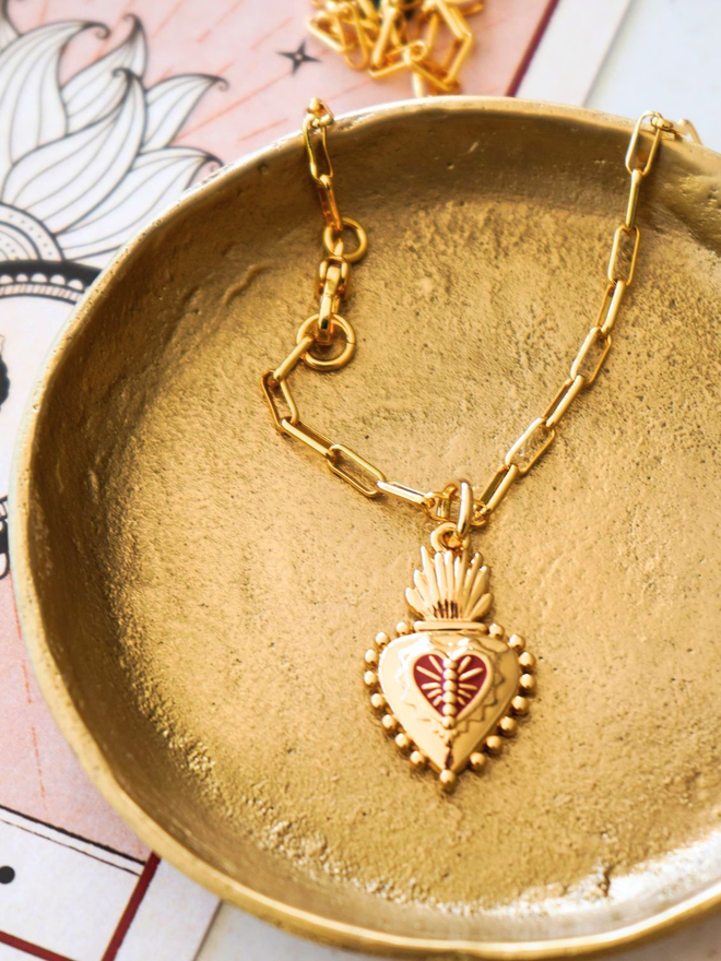 Gold plate with a gold and red Frida Kahlo charm necklace on it