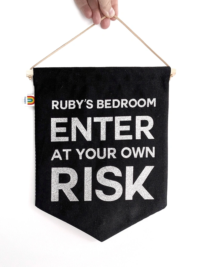 Black personalised wall hanging banner with the text “Ruby’s Bedroom Enter at Your Own Risk,” handmade fabric sign for kids’ rooms.