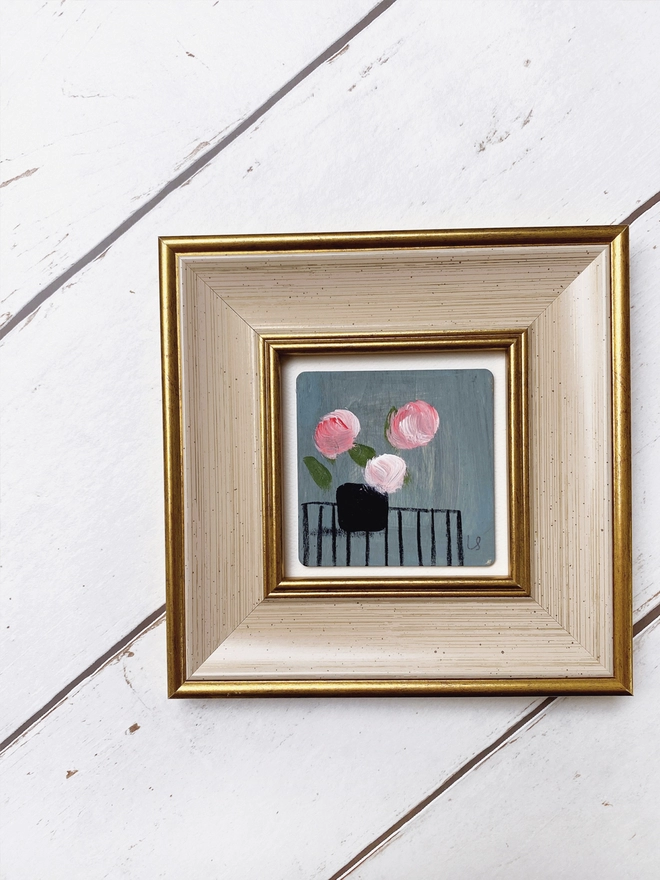 picture of three painterly pink flowers on dusty blue background in a cream and gold 1960's style frame