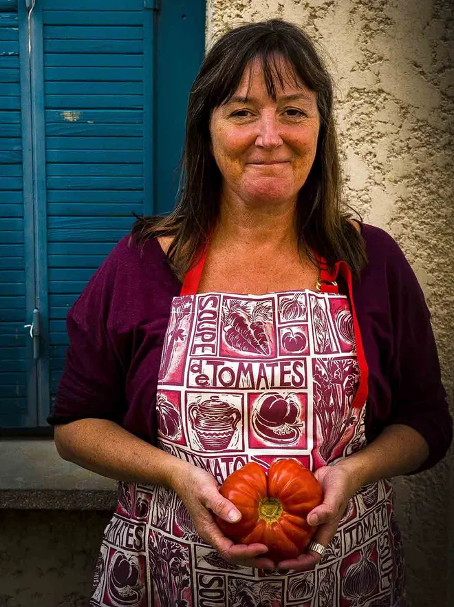 Kate Guy in her tomato soup apron holding a giant tomato